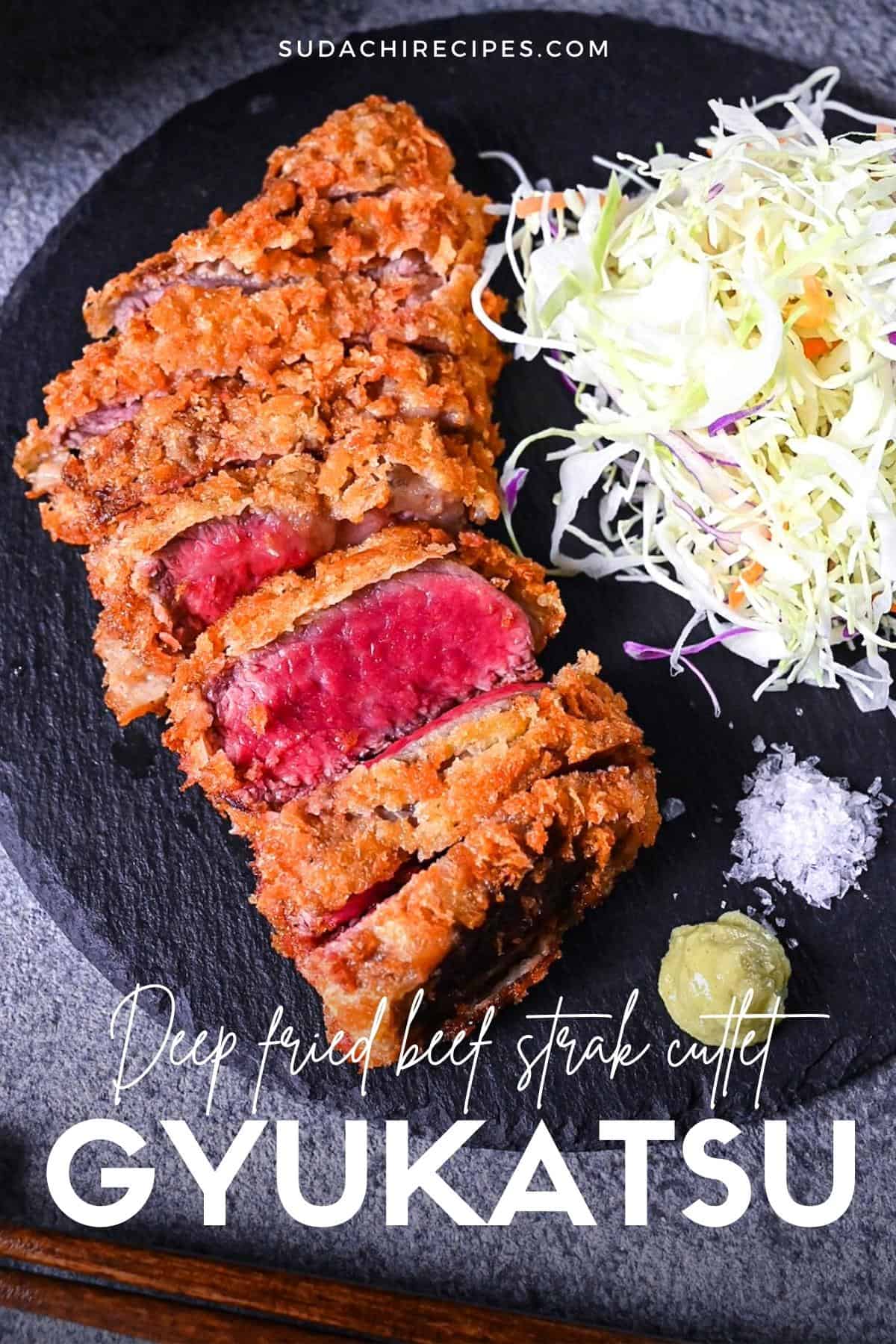 Gyukatsu (Japanese beef steak cutlet) served with cabbage, salt flakes and wasabi on a black slate plate