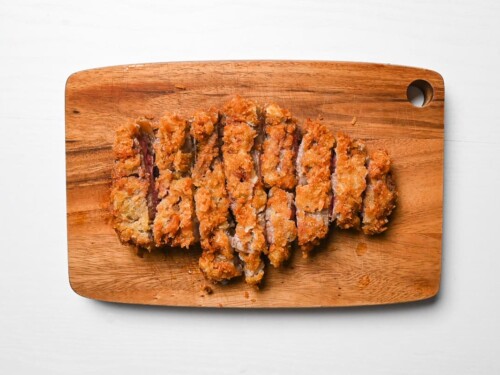 Japanese beef gyukatsu cut into strips on a wooden chopping board