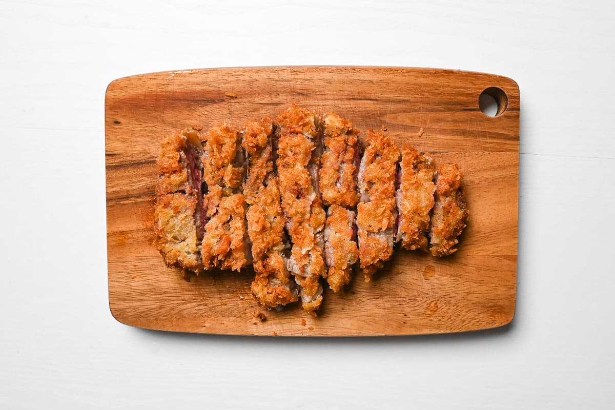 Japanese beef gyukatsu cut into strips on a wooden chopping board
