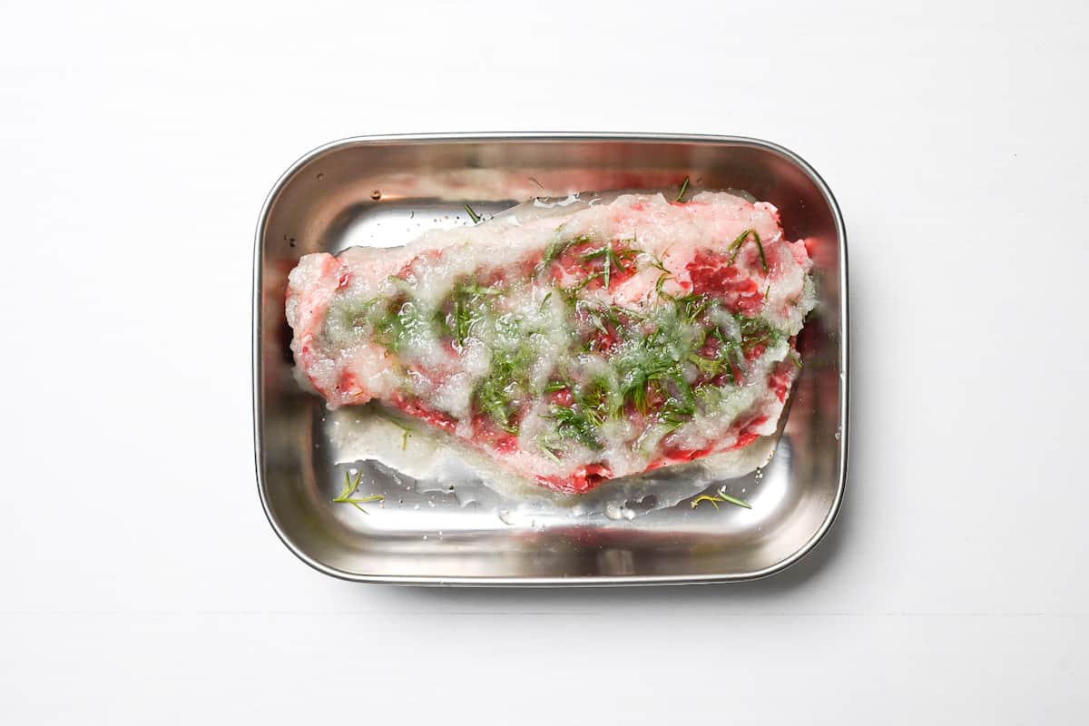 beef steak coated in grated onion in an aluminum container