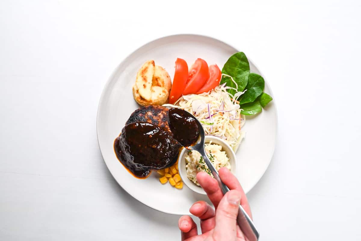 dishing up hamburg with potato salad, salad vegetables and wedges