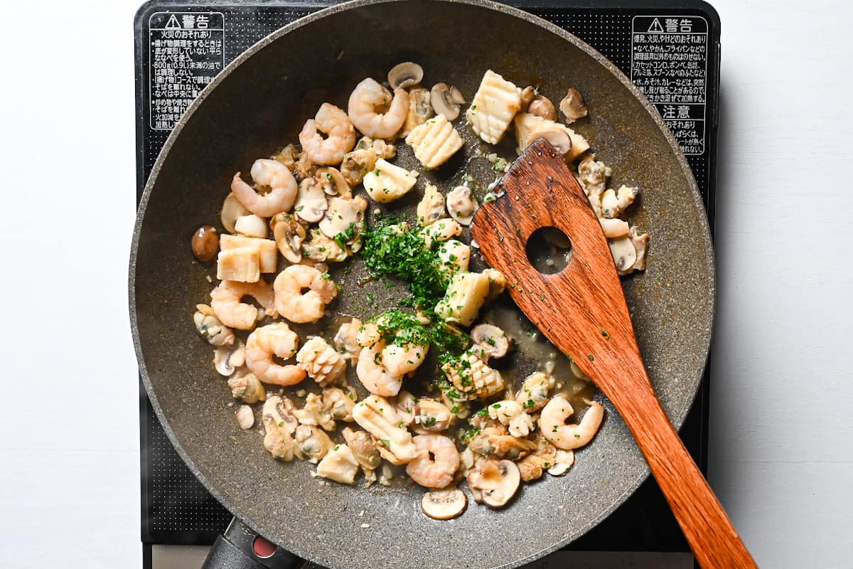adding salt and parsley to stir fried mixed seafood