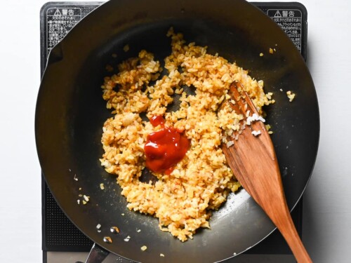 adding ketchup to spiced rice