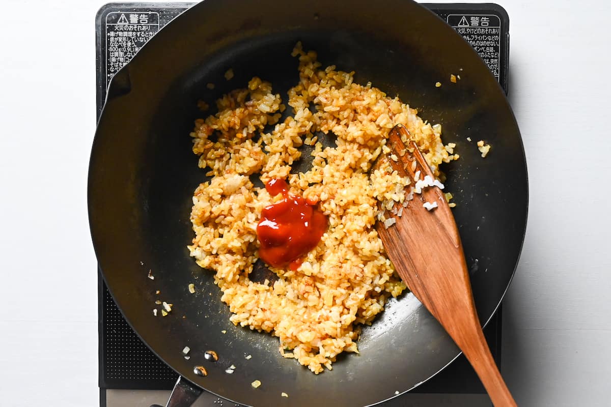 adding ketchup to spiced rice