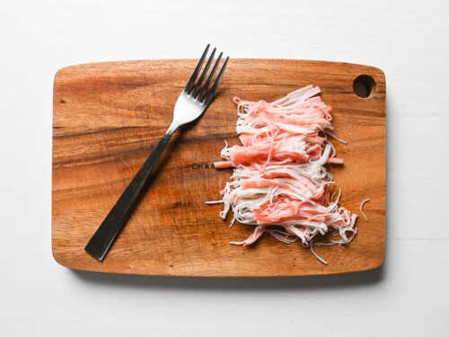 shredded imitation crab on a wooden chopping board