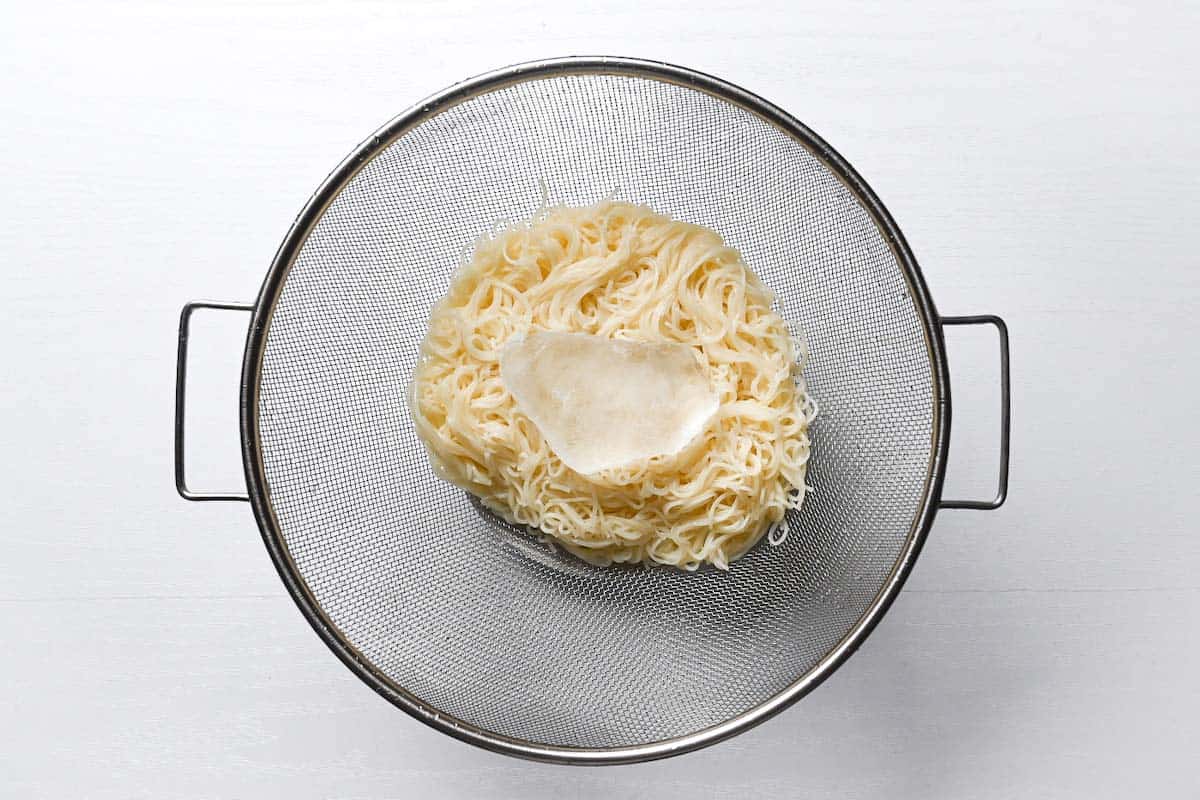 somen noodles being chilled with ice in a sieve