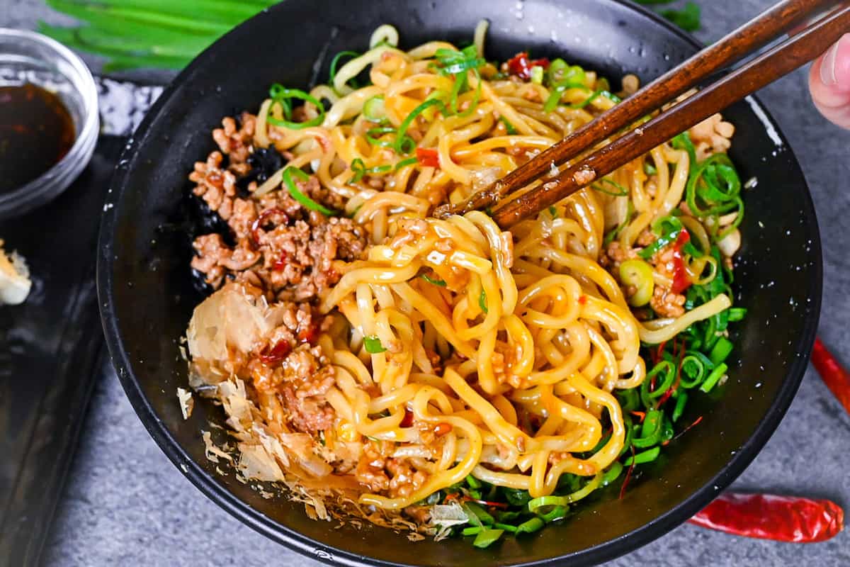 Mixing and lifting Taiwan mazesoba with wooden chopsticks