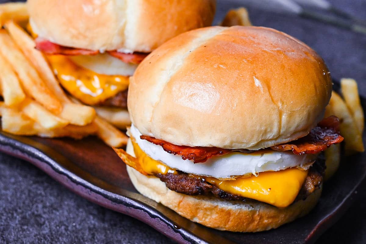 Japanese tsukimi burger on a brown rectangular plate with fries