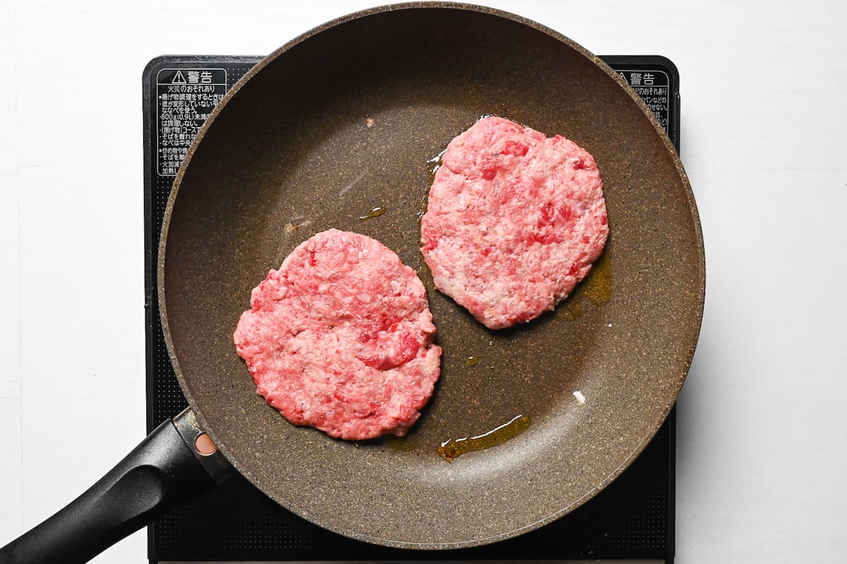 two beef patties in a frying pan