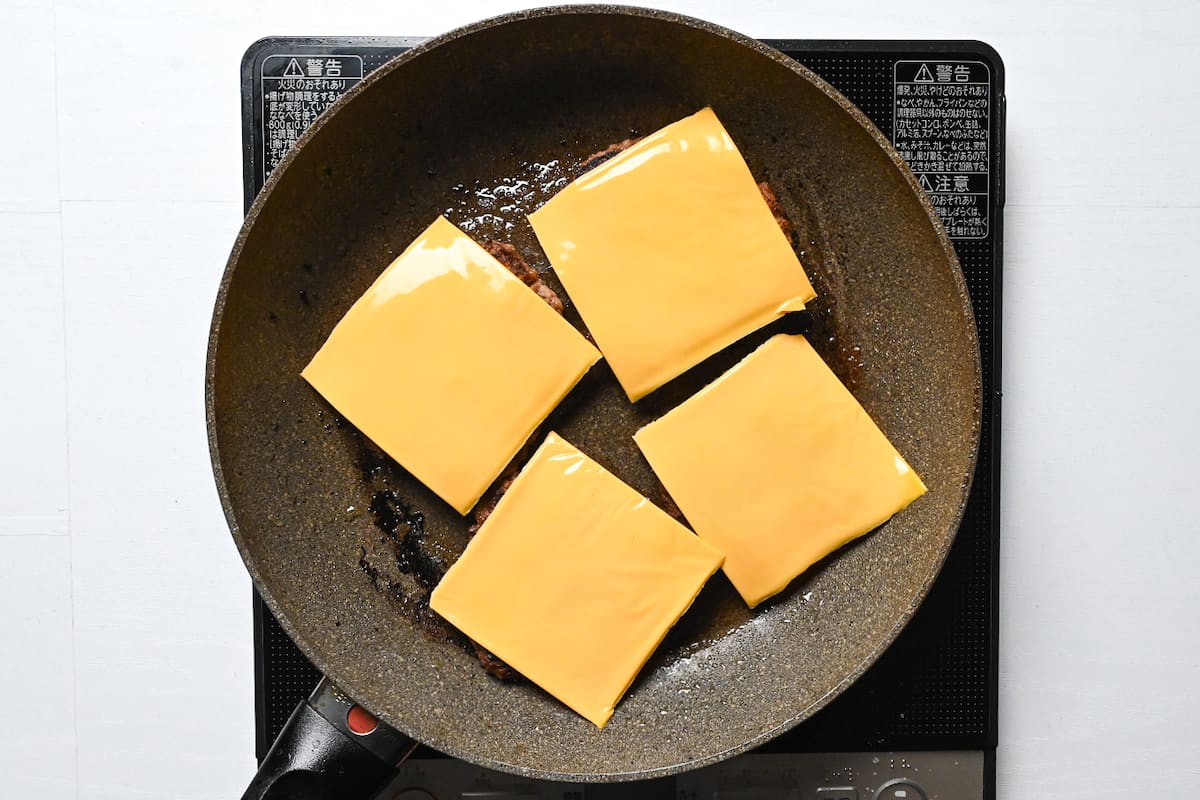 4 beef patties with cheese in a frying pan