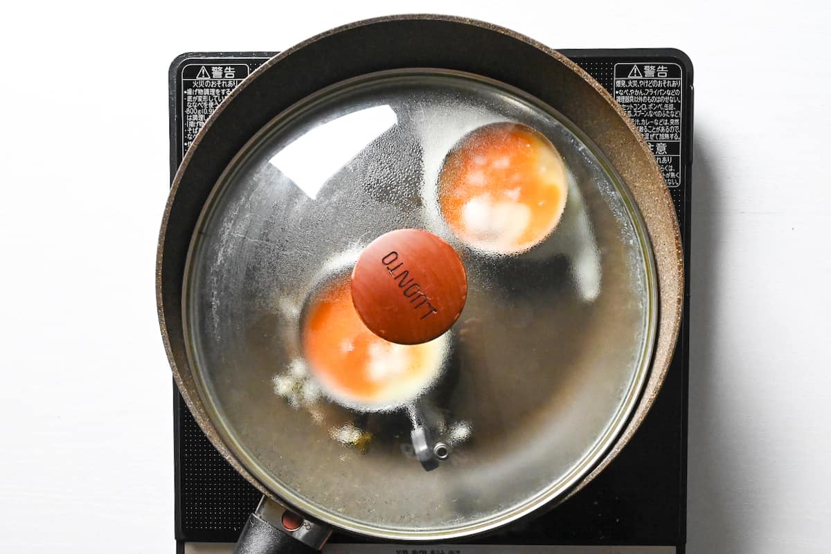 steaming eggs with lid on frying pan