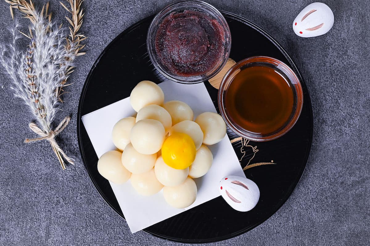 tsukimi dango moon viewing dumplings on a black tray decorated with gold rabbits top down view