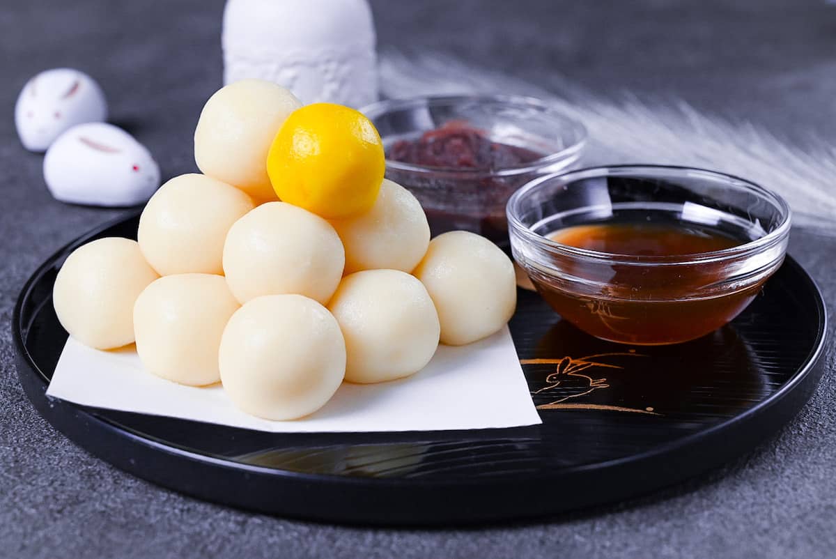 tsukimi dango moon viewing dumplings on a black tray decorated with gold rabbits