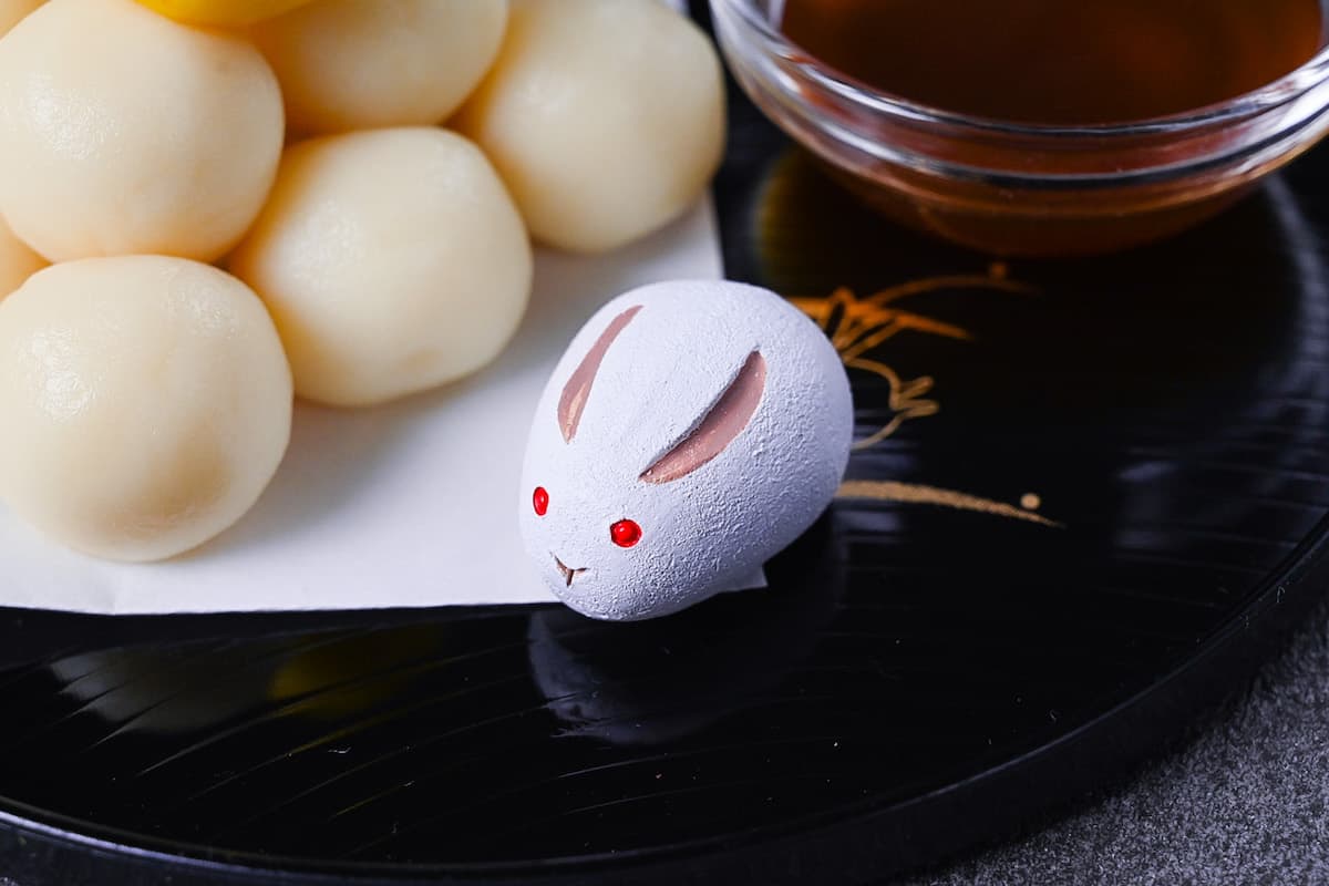 tsukimi dango moon viewing dumplings on a black tray decorated with gold rabbits