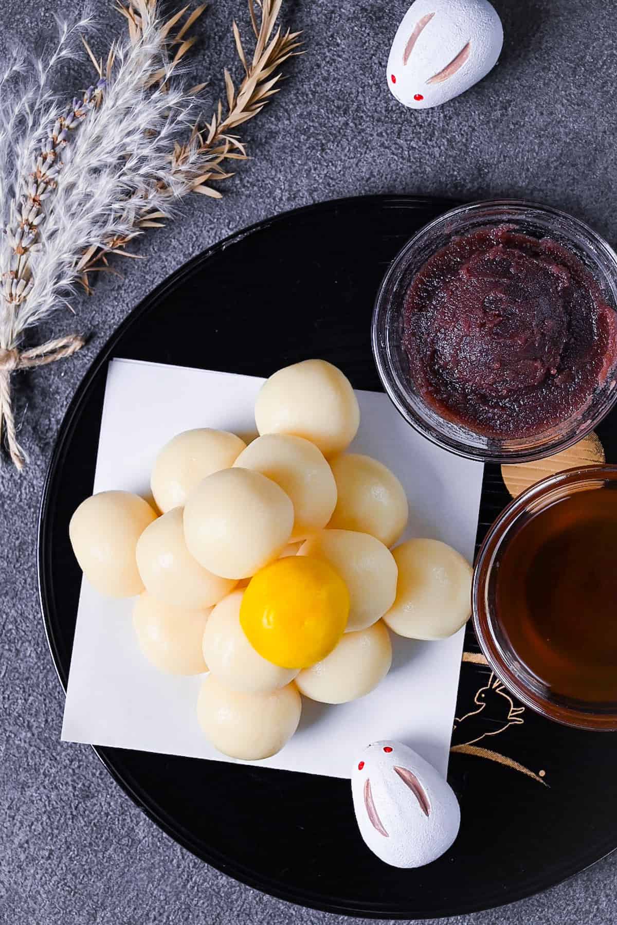 tsukimi dango moon viewing dumplings on a black tray decorated with gold rabbits