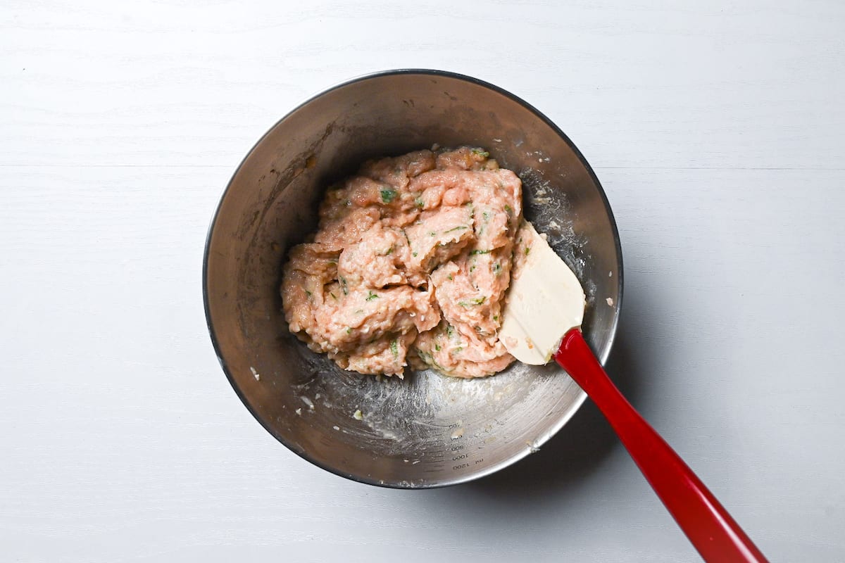 tsukune meatball mixture in a mixing bowl with silicone spatula