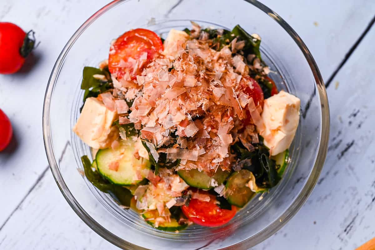 Japanese wakame seaweed salad made with tofu, cucumber and mini tomatoes in a small glass bowl top down