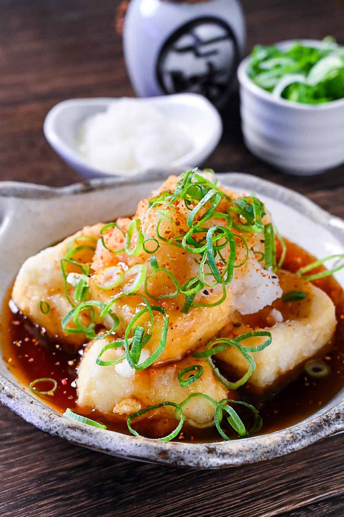 Agedashi Tofu (Japanese deep fried tofu) in a thick sauce topped with chopped spring onions, grated daikon and shichimi pepper