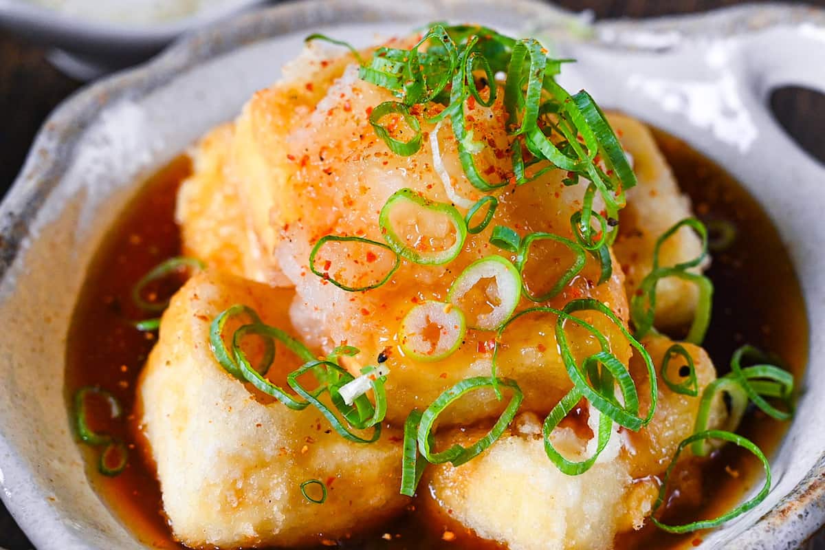 Agedashi Tofu (Japanese deep fried tofu) in a thick sauce topped with chopped spring onions, grated daikon and shichimi pepper