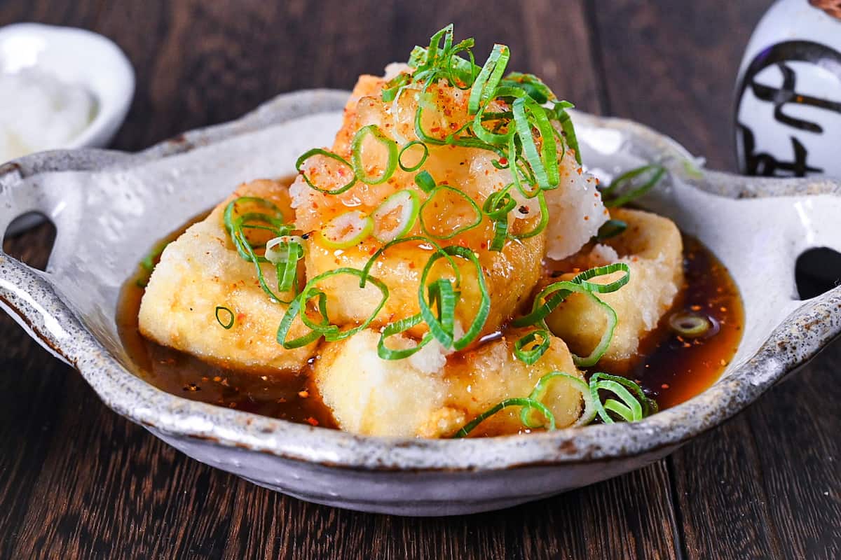 Agedashi Tofu (Japanese deep fried tofu) in a thick sauce topped with chopped spring onions, grated daikon and shichimi pepper