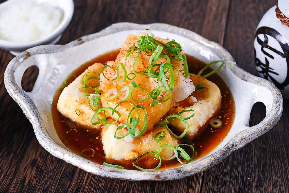 Agedashi Tofu (Japanese deep fried tofu) in a thick sauce topped with chopped spring onions, grated daikon and shichimi pepper