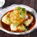 Agedashi Tofu (Japanese deep fried tofu) in a thick sauce topped with chopped spring onions, grated daikon and shichimi pepper