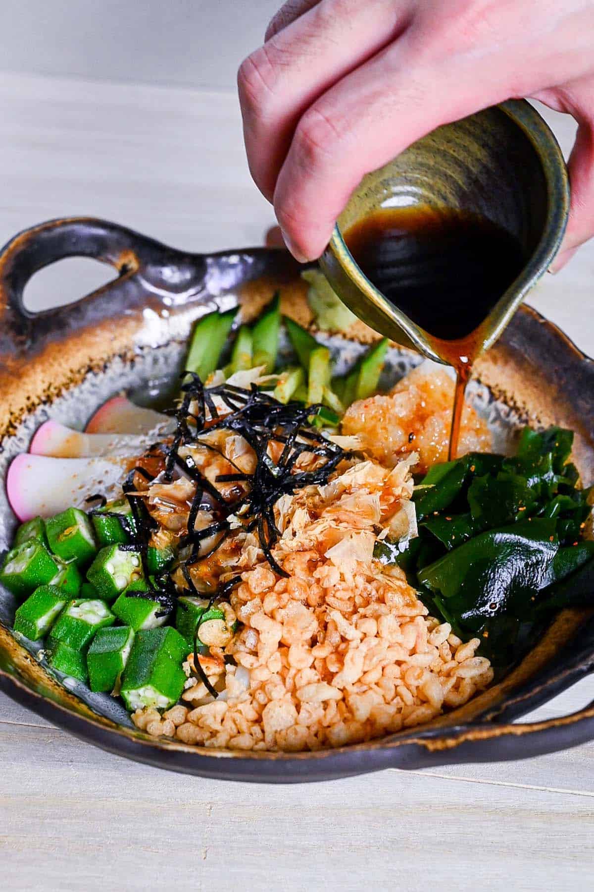 pouring homemade dashi sauce over hiyashi tanuki udon