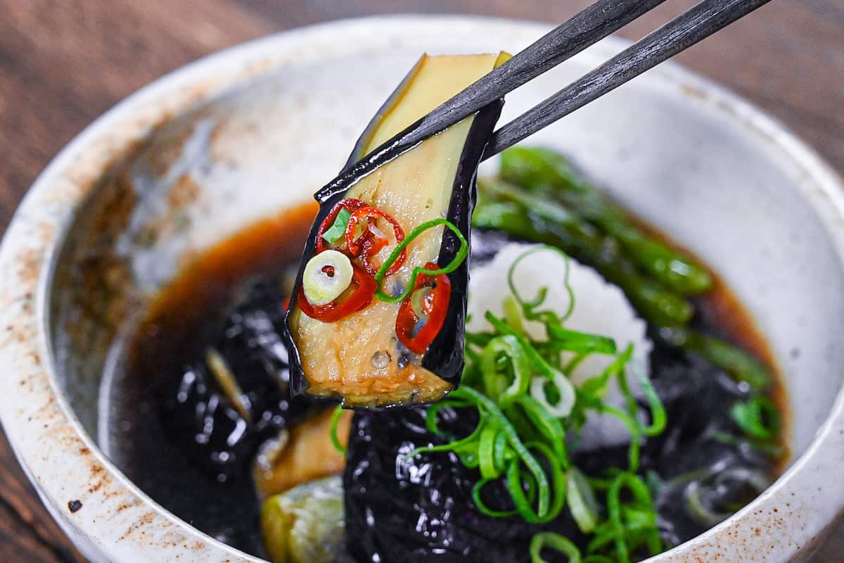 nasu no agebitashi served in a cream bowl and topped with grated daikon and chopped spring onion