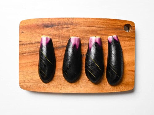 eggplant with scored skin on a wooden chopping board