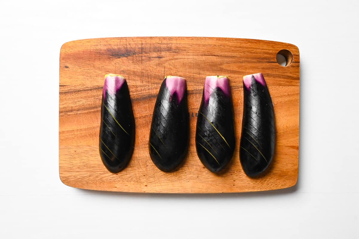 eggplant with scored skin on a wooden chopping board