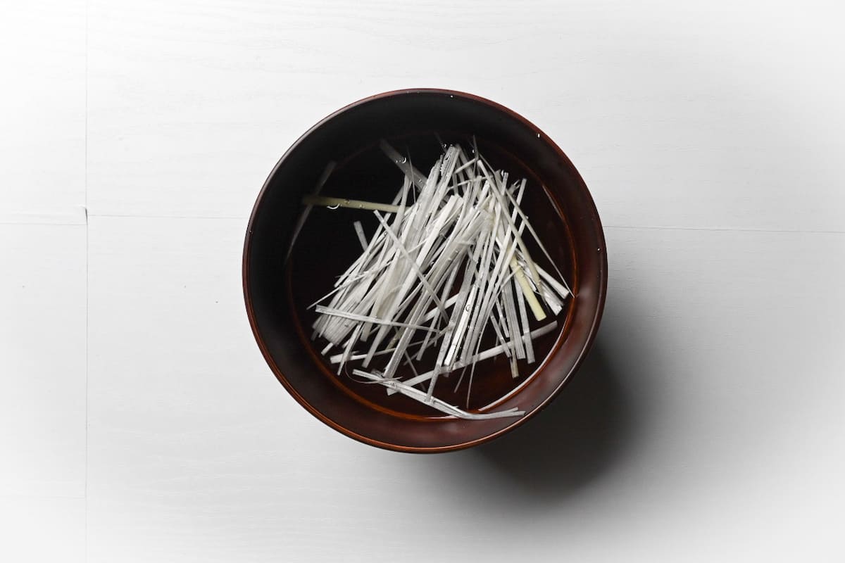 Shiraganegi (white part of spring onion) soaking in a bowl of water