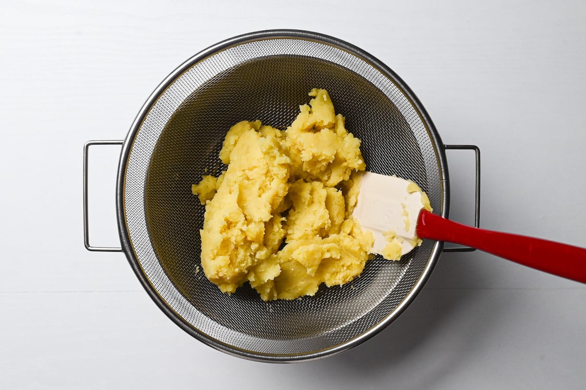 Mashed sweet potato mixture in a mesh sieve