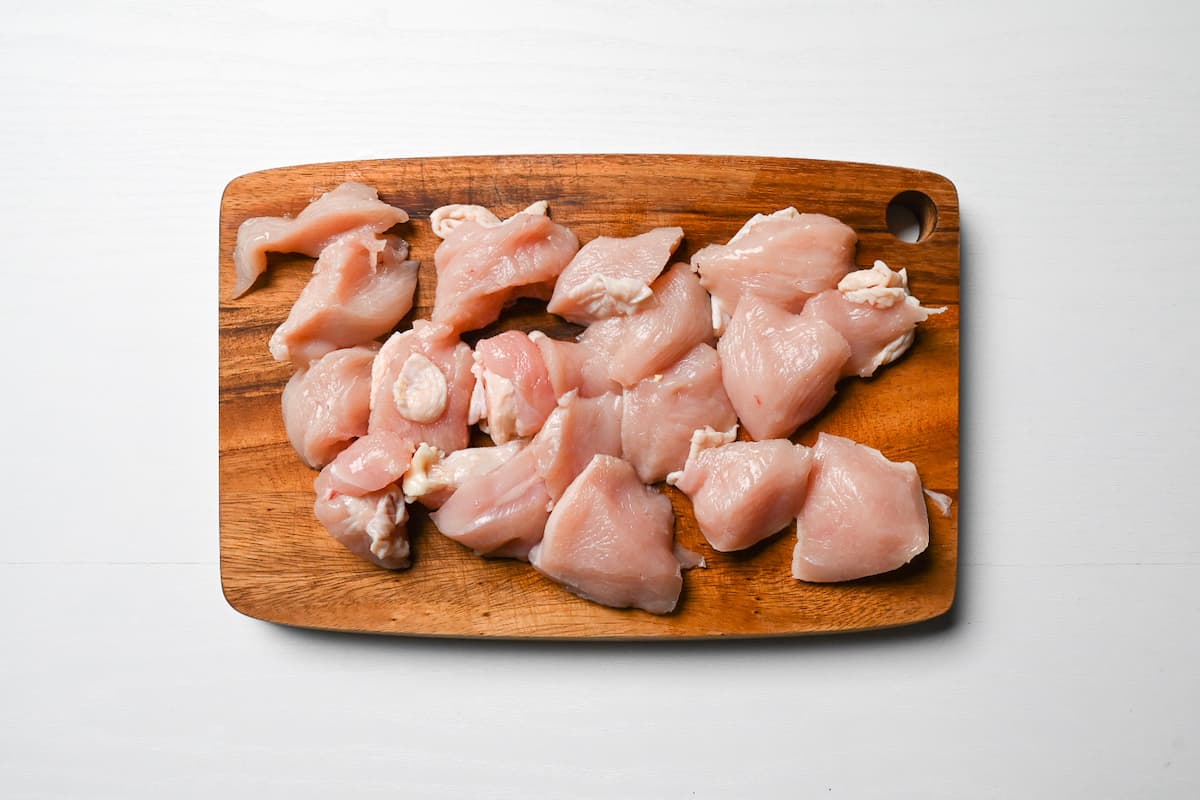 chicken breast cut into bitesize pieces on wooden chopping board