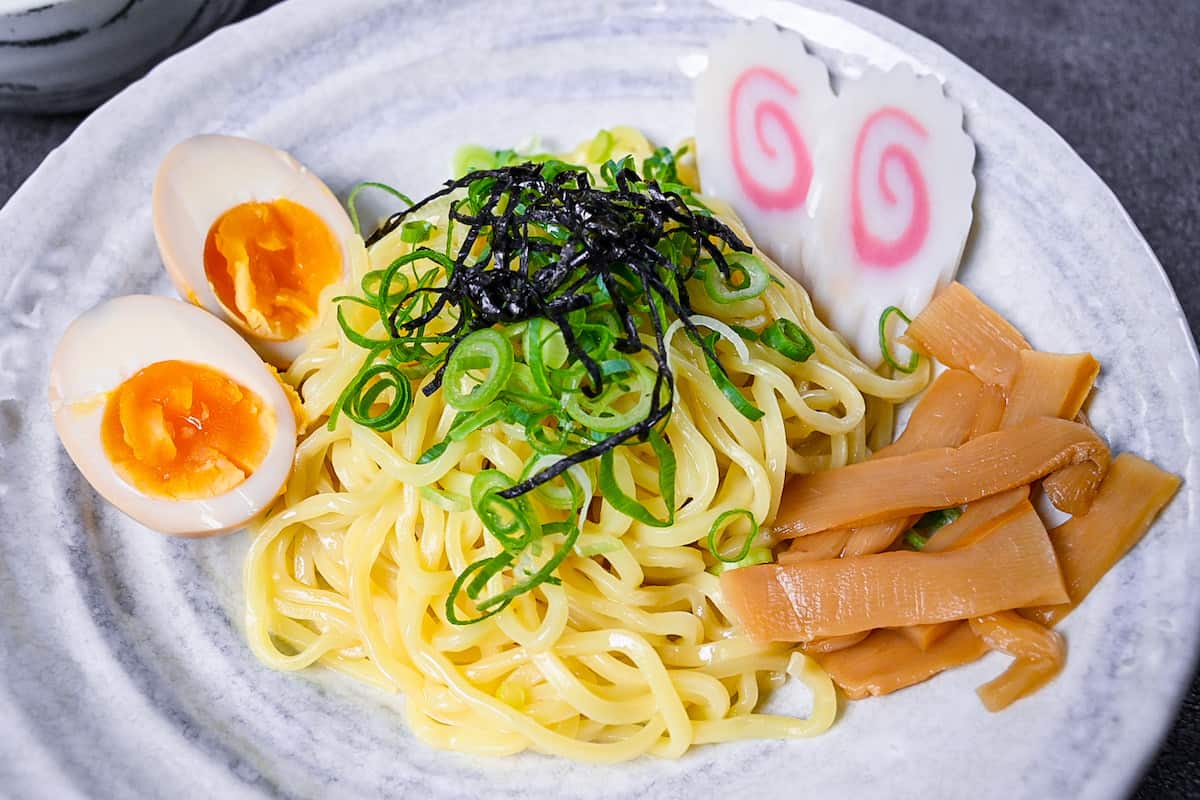 Japanese ramen noodles on a white plate with menma, narutomaki and ramen eggs close up