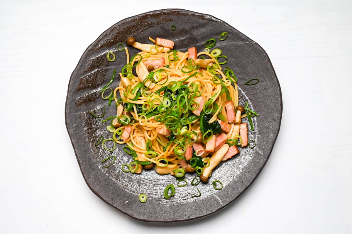 Butter shoya pasta on a black Japanese style plate topped with chopped spring onions
