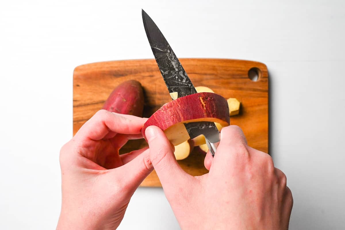 Peeling skin off slices of sweet potato using pairing knife