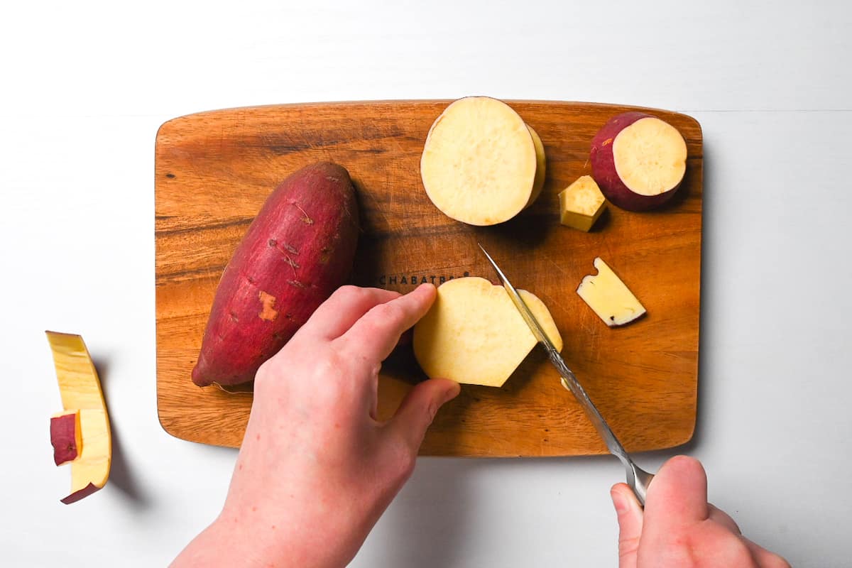 cutting edges off slices of Japanese sweet potato on a wooden chopping board
