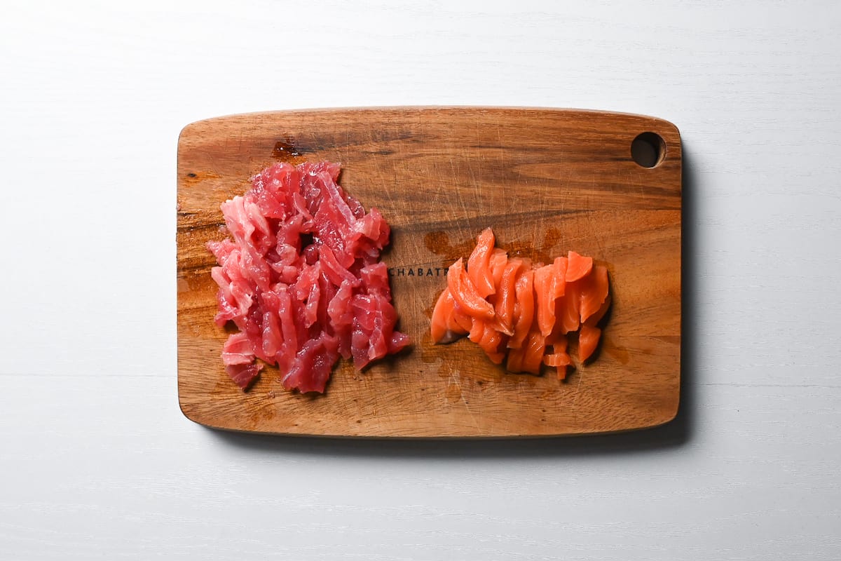 tuna and salmon sashimi cut into strips on a wooden chopping board