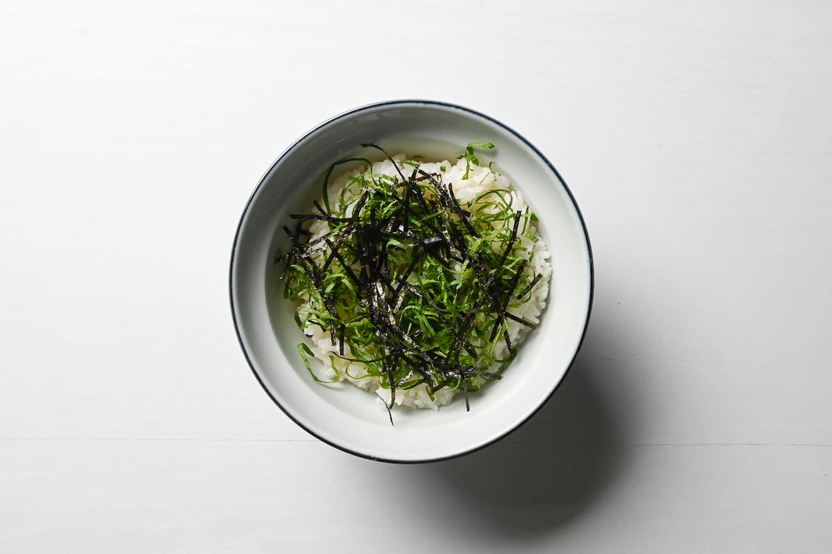a bowl of rice topped with chopped spring onions and kizami nori
