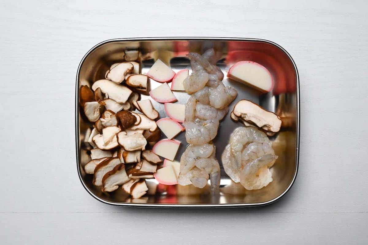 Shiitake mushroom, kamaboko and raw shrimp cut into small pieces and placed inside a silver container