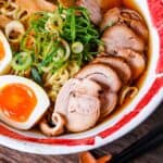 Homemade chicken chashu served on top of shoyu ramen in a white and red bowl