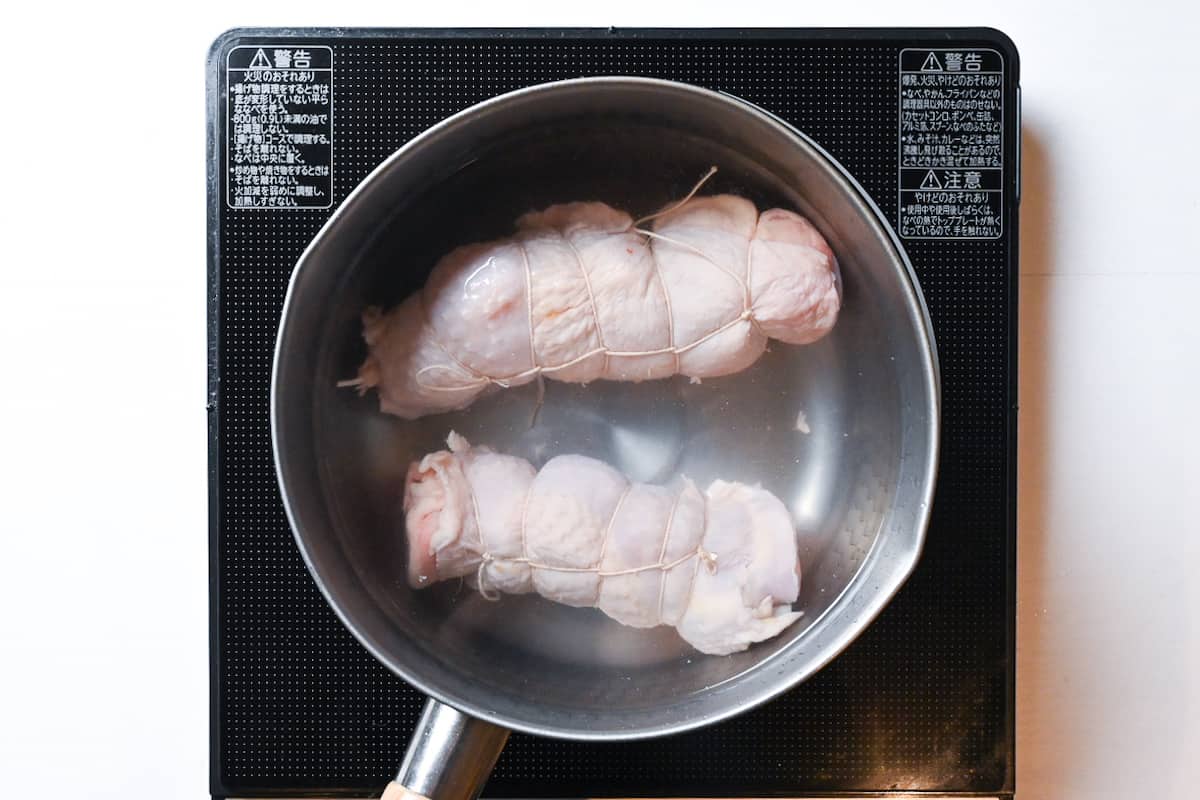 Rolled chicken thigh boiling in a pot of water