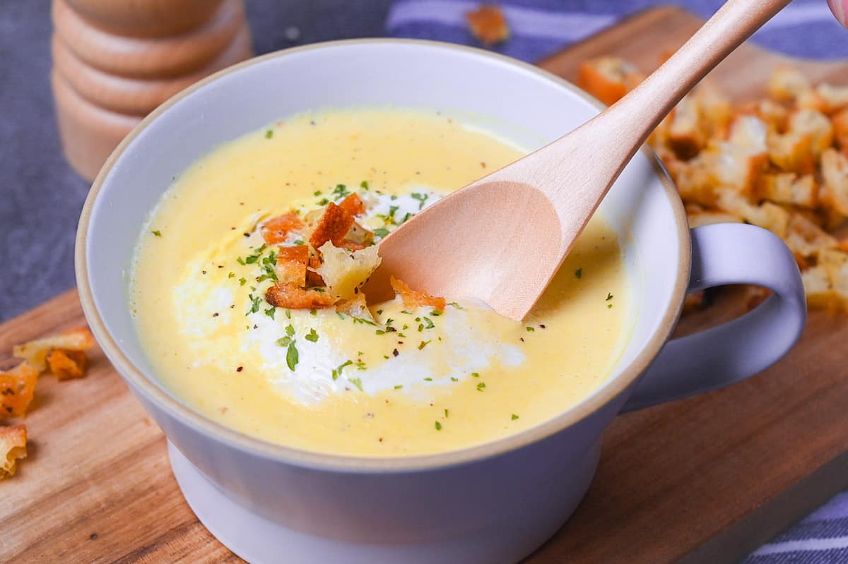 Japanese corn potage in a grey soup cup topped with fresh cream, homemade croutons and parsley