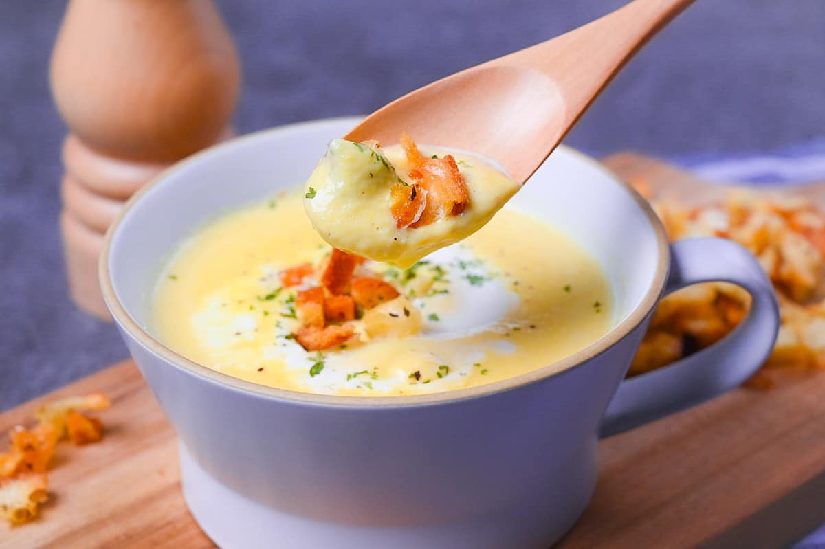 Japanese corn potage in a grey soup cup topped with fresh cream, homemade croutons and parsley