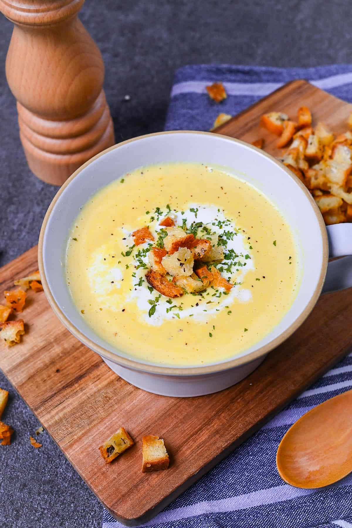 Japanese corn potage in a grey soup cup topped with fresh cream, homemade croutons and parsley