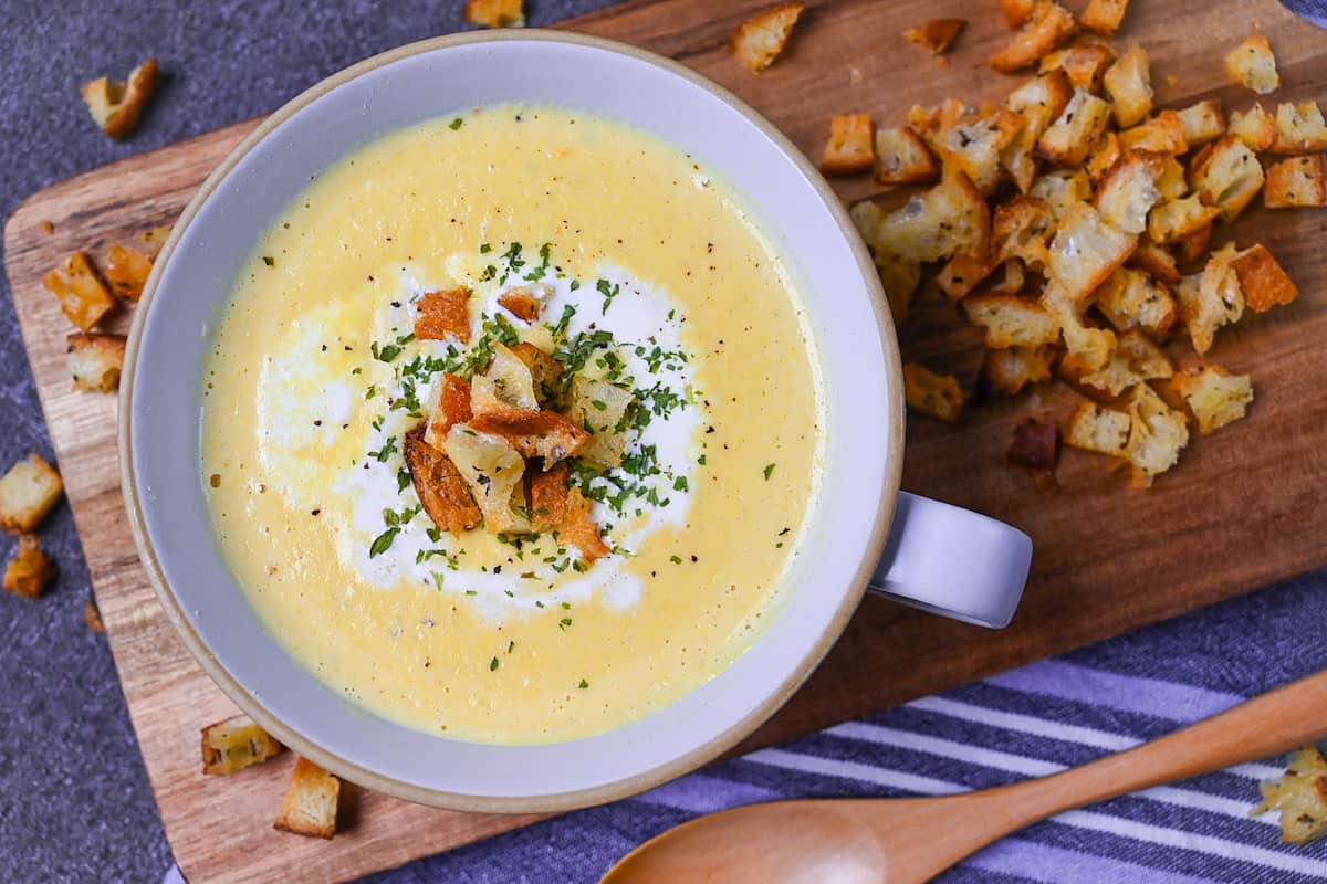 Japanese corn potage in a grey soup cup topped with fresh cream, homemade croutons and parsley