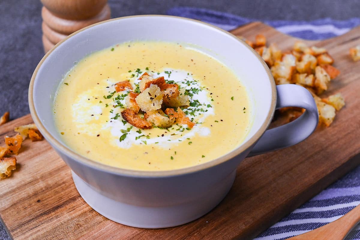 Japanese corn potage in a grey soup cup topped with fresh cream, homemade croutons and parsley