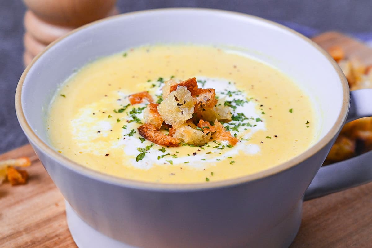 Japanese corn potage in a grey soup cup topped with fresh cream, homemade croutons and parsley