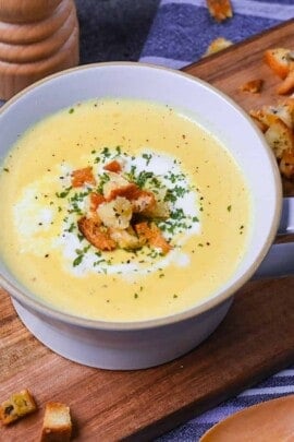 Japanese corn potage in a grey soup cup topped with fresh cream, homemade croutons and parsley