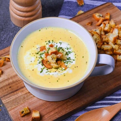 Japanese corn potage in a grey soup cup topped with fresh cream, homemade croutons and parsley